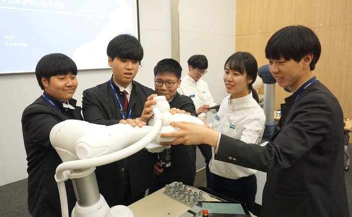 두산로보틱스 본사(경기도 수원)에서 열린 로봇 아카데미에 참가한 삼일공업고등학교 학생들이 두산로보틱스 연구원들과 함께 협동로봇을 시연하고 있다.
